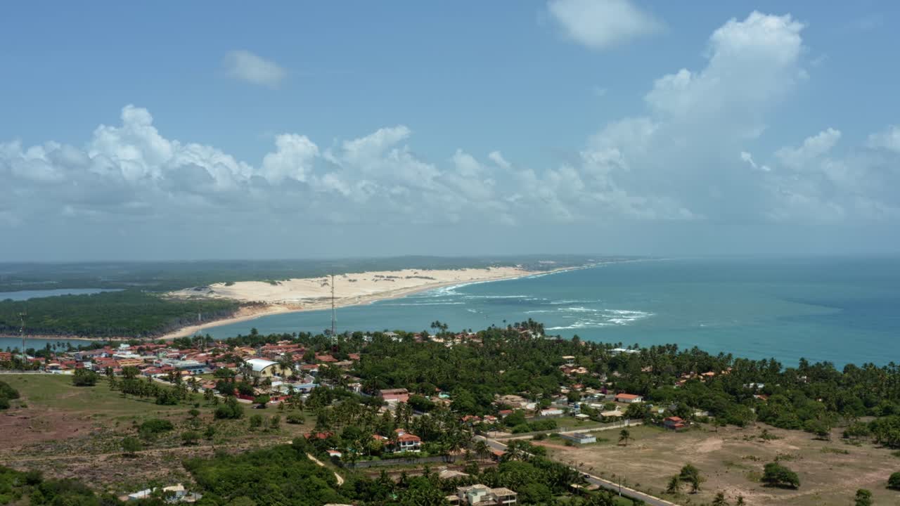 Rising aerial drone extreme wide shot of the tropical beach town of Tibau do Sul in Rio Grande do Norte, Brazil with the Malemb&aacute; Sand Dunes, Atlantic Ocean, and Guara&iacute;ras Lagoon in the background