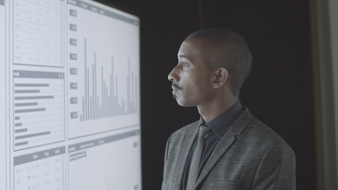 Serious black financial trader analyzing trading charts