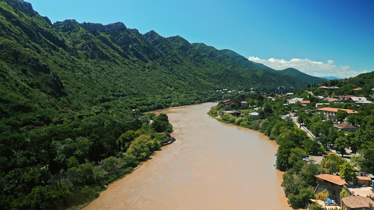 Scenic River Valley with Mountains and Village under Blue Sky