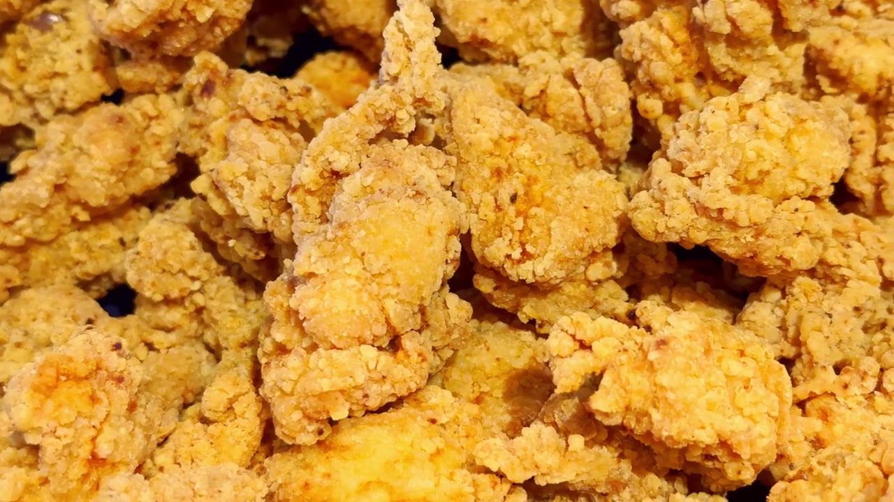 Primo piano di pollo fritto fresco con una panatura dorata e croccante, che mostra una consistenza croccante, carne succosa e un appetitoso pasto fatto in casa
