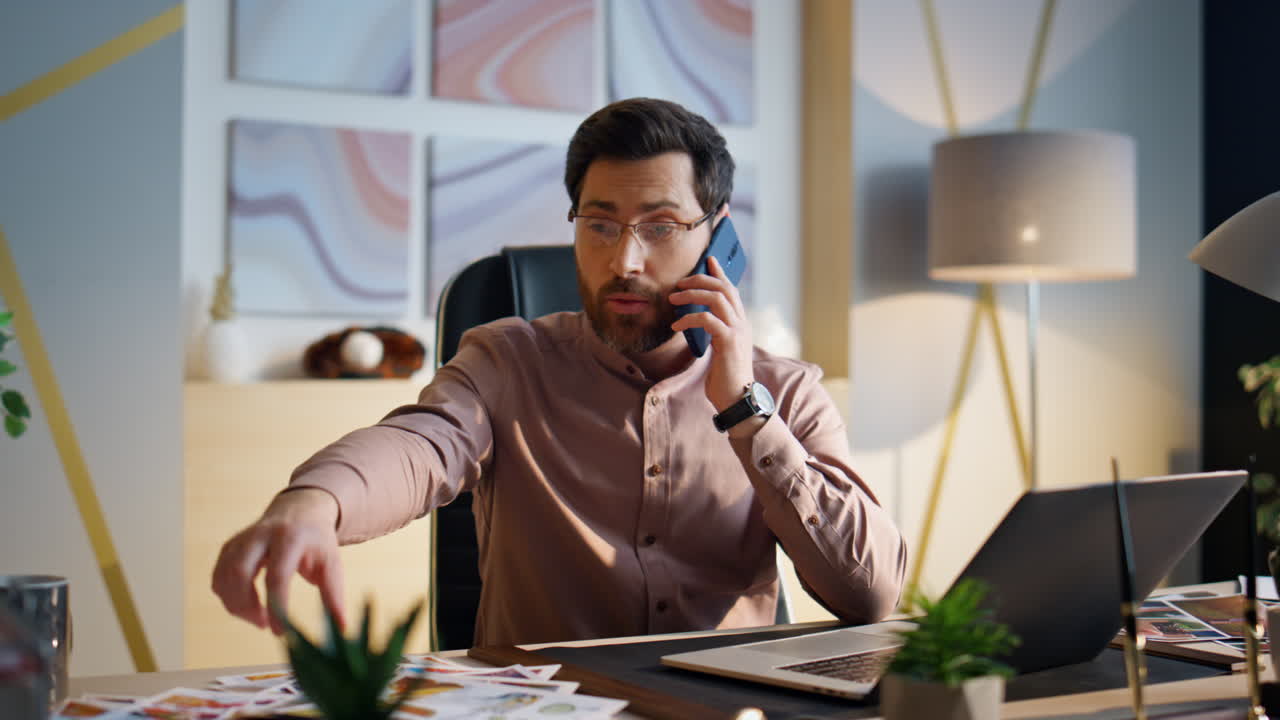 Nærbillede af travl virksomhedsmedarbejder, der taler i mobiltelefon og arbejder ved kontorbord.