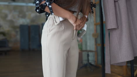 woman trying on beige pants in a fitting room