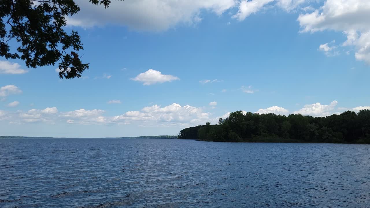 Video of running water in lake with an overcast sky with multiple ground in the distance