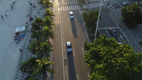 Autos-En-Una-Concurrida-Avenida-En-Río-De-Janeiro,-Hora-Del-Atardecer-Grandes-Sombras-Hora-Dorada-Cerca-De-La-Playa---Toma-Aérea-De-Drones