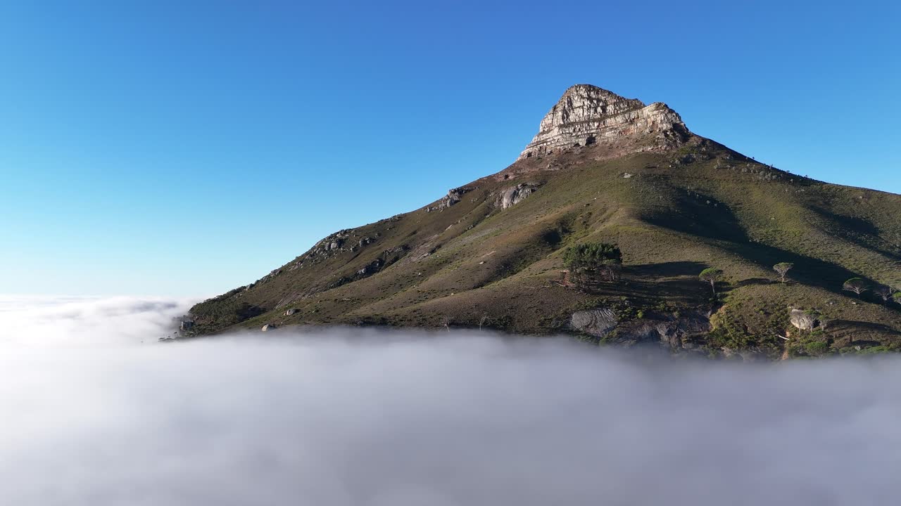 Aerial drone footage of Lion’s Head mountain in Cape Town, South Africa, surrounded by mist and clouds with only the peak emerging above the fog cinematic high angle view of iconic landscape