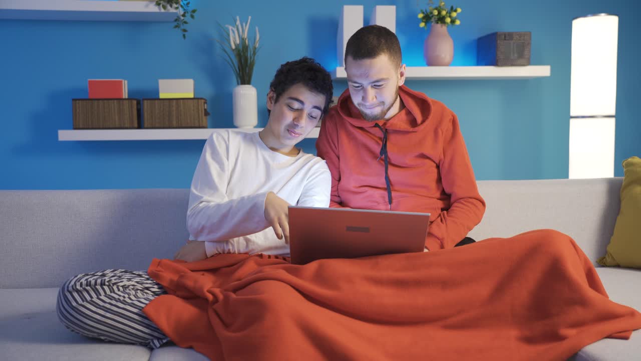 dos hermanos navegando por las redes sociales y sitios de citas en una computadora portátil.