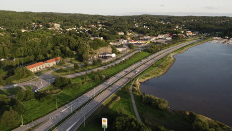 cars driving through e6 highway through ljungskile along the bay in sweden. - aerial shot