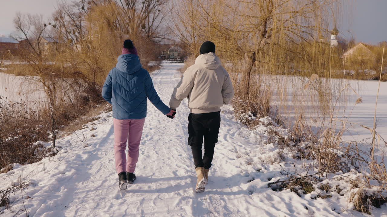 Um casal caminhando na neve de inverno