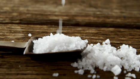 salt in spoon on wooden table 4k