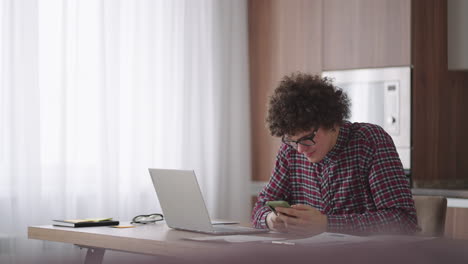 young man with smartphone in his hands. modern businessman or student at home office. freelancer at work. young student man study at home with laptop and uses a smartphone