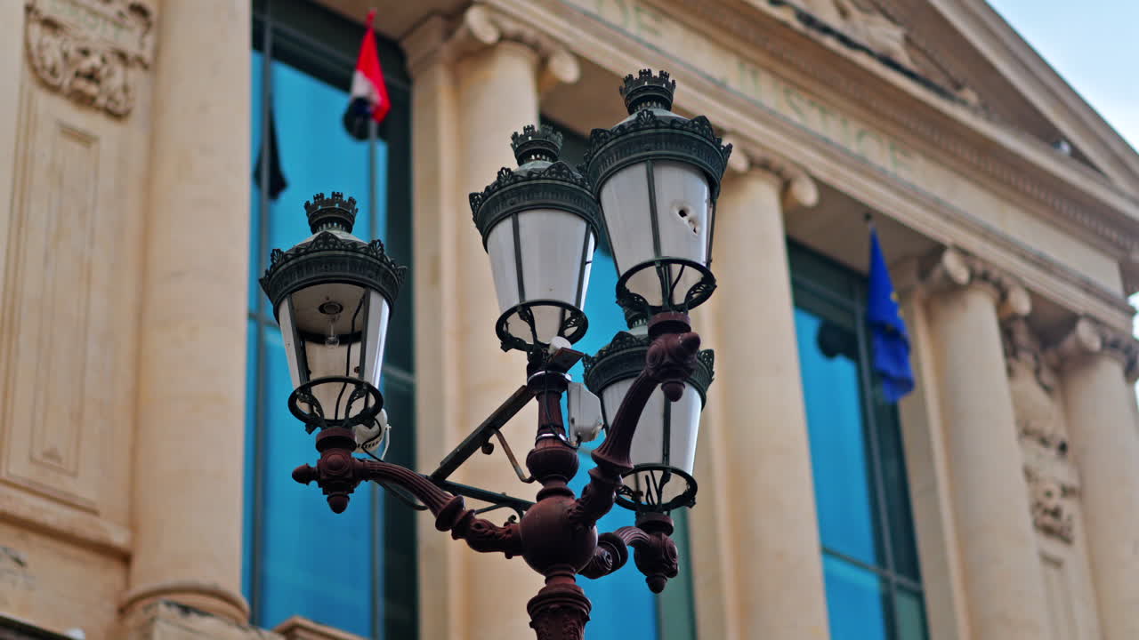 Close up of a street lamp with a blurred view of the Nice courthouse on the background