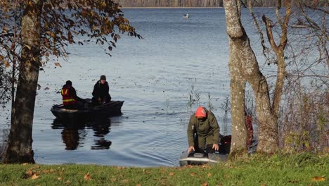 fishermen in a boat on a blue lake, casting lines and catching fish on a calm day. the water reflects the autumn landscape, enhancing the serene and seasonal feel.