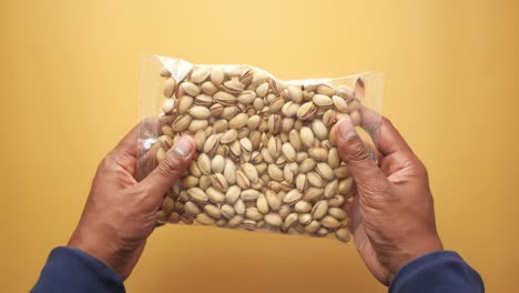 close-up of a hand holding a bag of pistachios