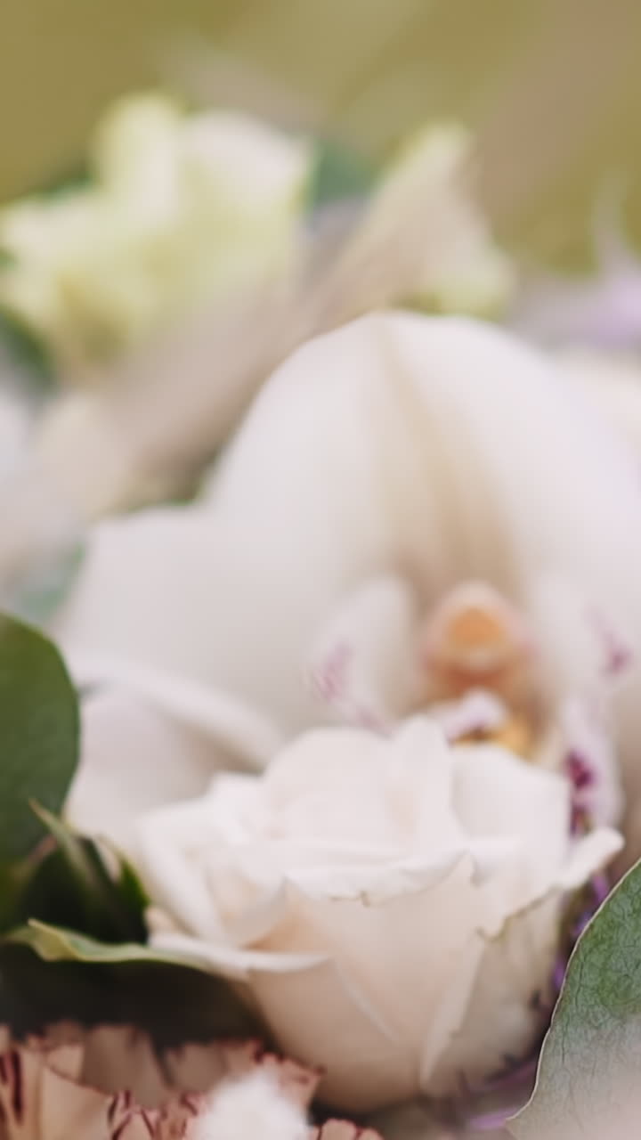 Woman with elegant manicure touches fresh flowers bouquet on store display closeup. Lady chooses present for greeting holiday party in floral shop