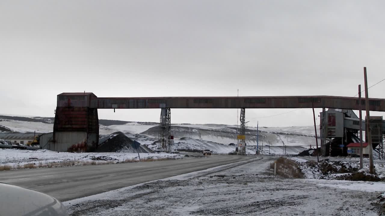 도로 위를 지나가는 차량과 함께 겨울에 오래된 폐광을 가로지르다