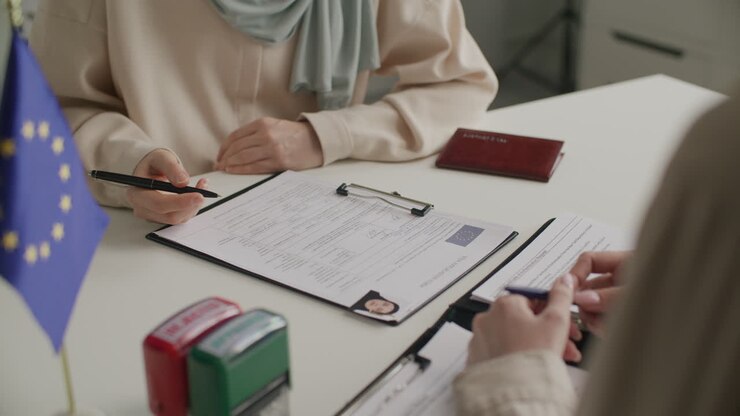 Ansøger underskriver EU-visumansøgningsformular med assistance fra konsulær medarbejder