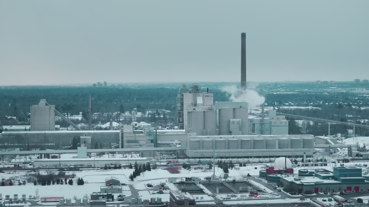 Industrial plant in snowy winter, smoke rising, climate impact