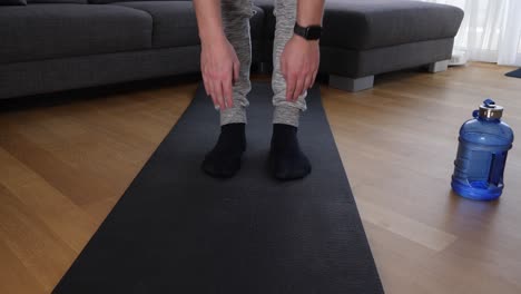 leg view of a male athlete doing stretching exercises on a sports mat in the living room