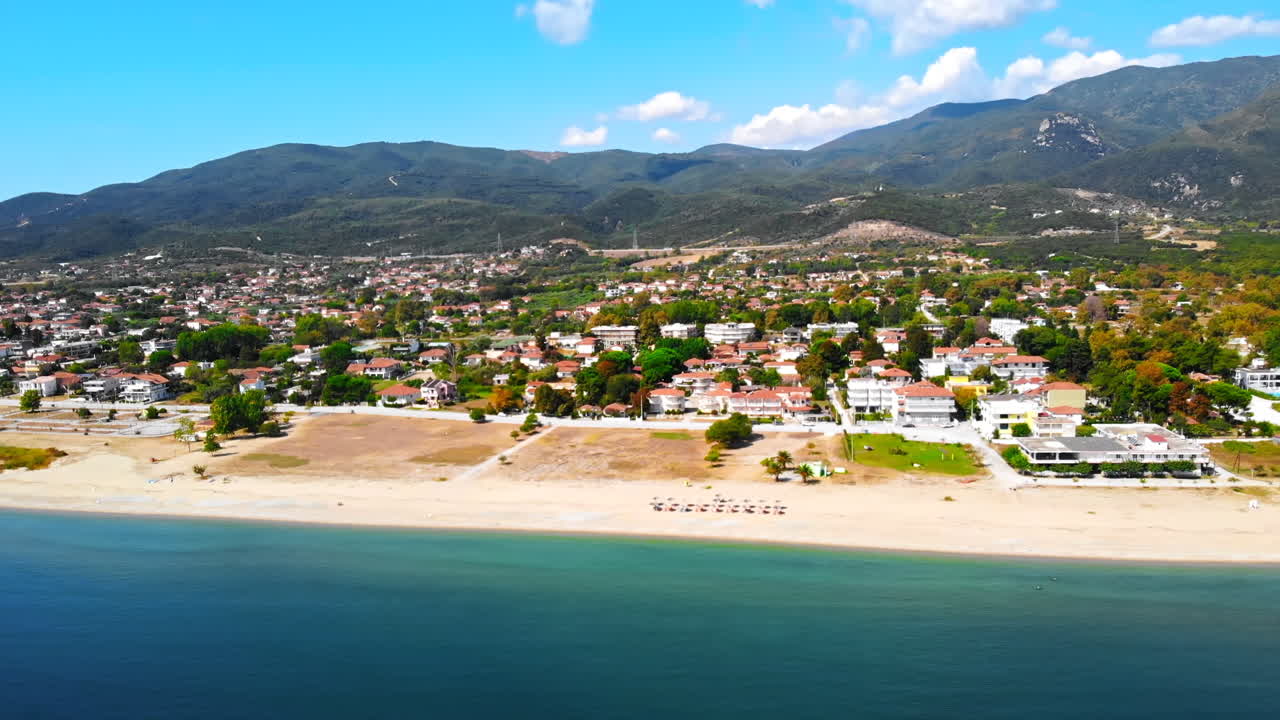 Panorama of the Asprovalta with multiple buildings and greenery, green hills on the background. Aegean sea coast. Sunny day. Greece