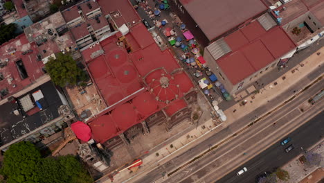 Tilt-down-and-panning-shot-of-buildings-in-downtown.-Red-roofed-buildings-by-main-road.--Colourful-mix-of-sunshades-on-market-place.-Mexico-City,-Mexico.