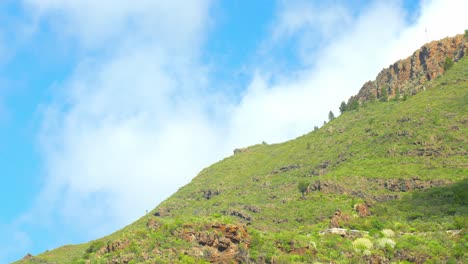 Clouds-flow-over-green-mountain-slope,-time-lapse-view