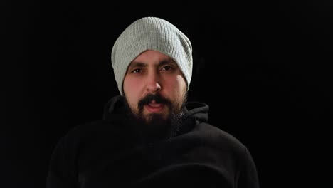 Bad-behavior-of-young-man-looking-angry-straight-to-camera,-smoking-cigarette-on-a-black-background