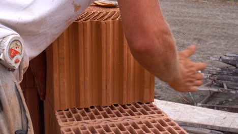 worker placing ceramic brick onto adhesive foam layer during wall construction
