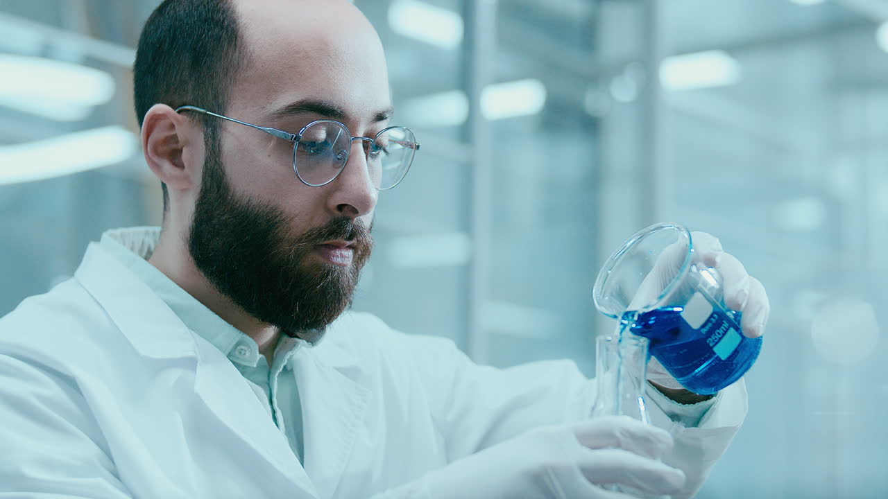Científico vertiendo solución química azul en un matraz durante un experimento de laboratorio