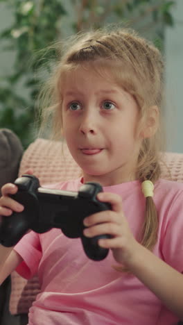 niños enfocados compiten jugando videojuegos divertidos con consolas en casa. niña en edad preescolar y niño pequeño usan dispositivos de juego para controlar el proceso de primer plano