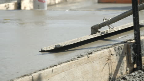 close up cement float over wet concrete at newly laid house slab slow motion