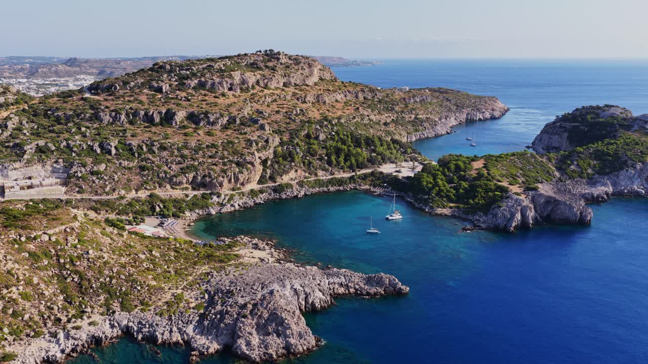 Aerial view of a scenic coastline with turquoise water and sailboats