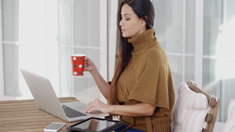 mujer atractiva sentada escribiendo en una computadora portátil