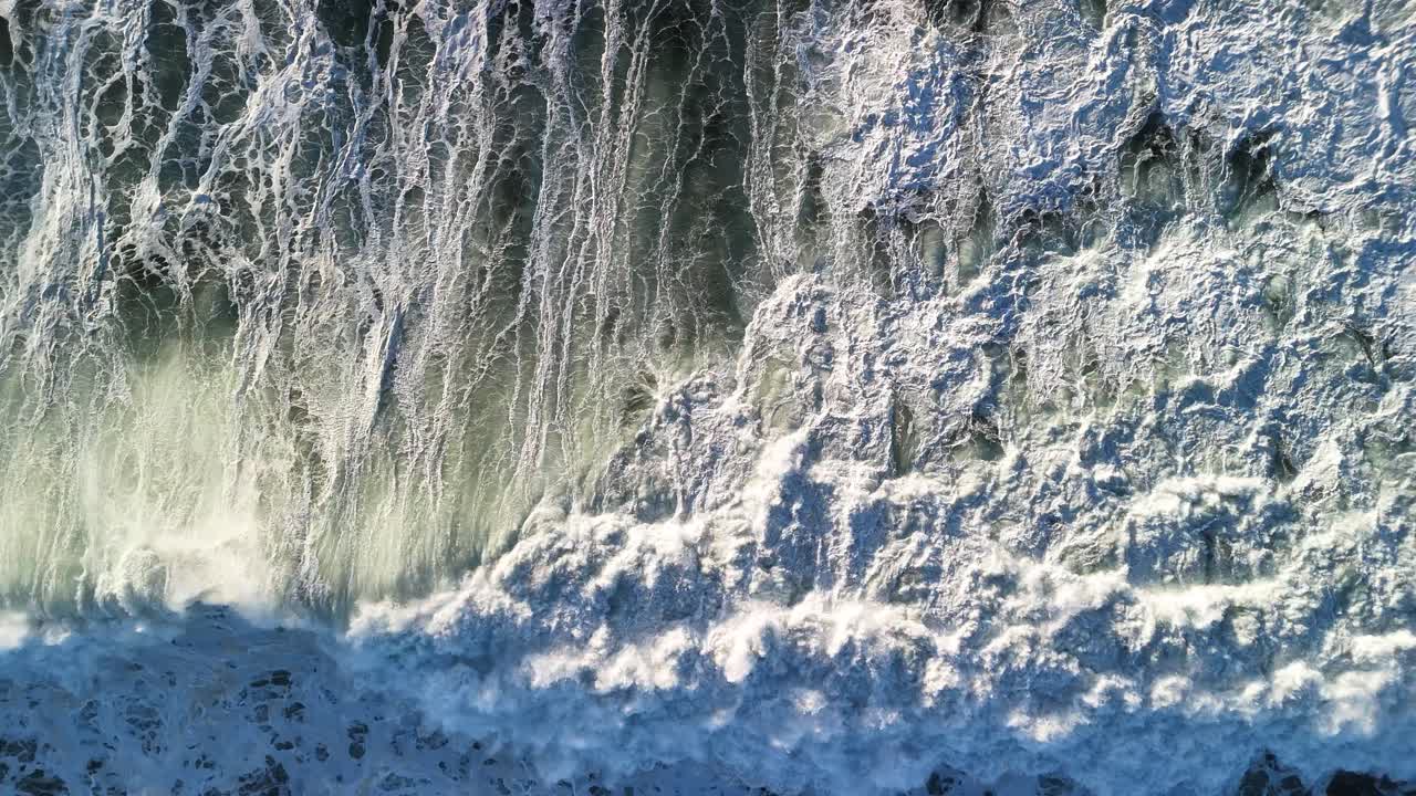 Raw energy of large waves crashing in the sea creating unique pattens amongst the foaming ocean surface. Aerial view