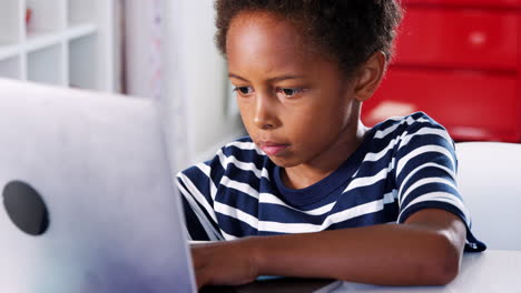 Un-Joven-Sentado-En-Un-Escritorio-En-El-Dormitorio-Usando-Una-Computadora-Portátil