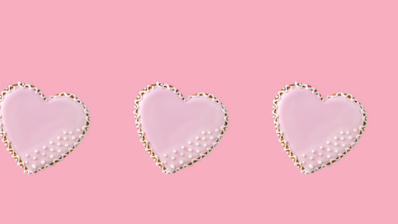 파스텔 바탕에 분홍색 글레이즈로 장식된 한 줄의 심장 모양의 쿠키와 함께 원활한 루프 애니메이션