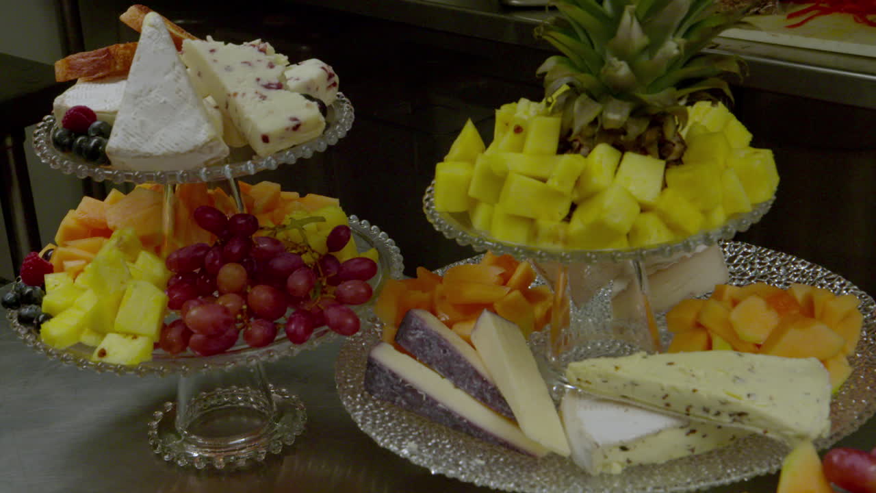 Hand adding food to cheese and fruit platter on display in restaurant