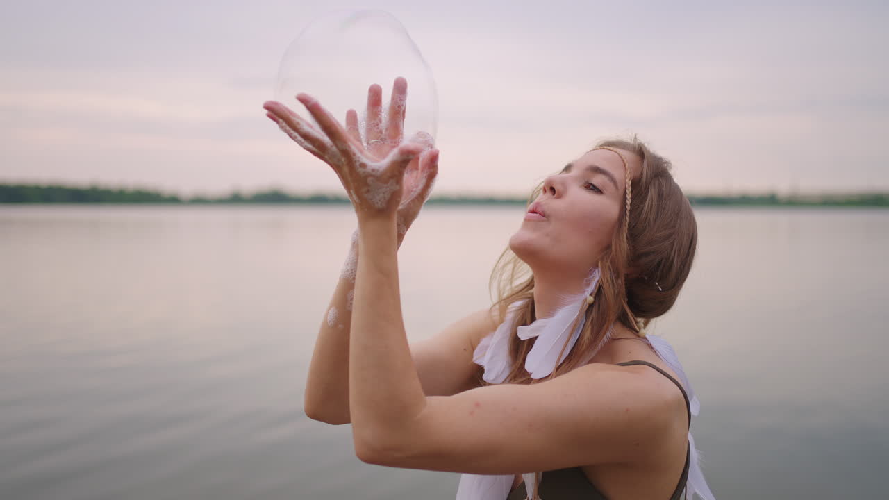 una joven artista muestra trucos de magia usando burbujas de jabón. cree burbujas de jabón en sus manos e inflelas ubicación espectáculo de circo teatral al atardecer