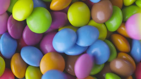 slow motion close-up of round colorful chocolate candies, dragee. rotation and fall multicolored chocolate candies