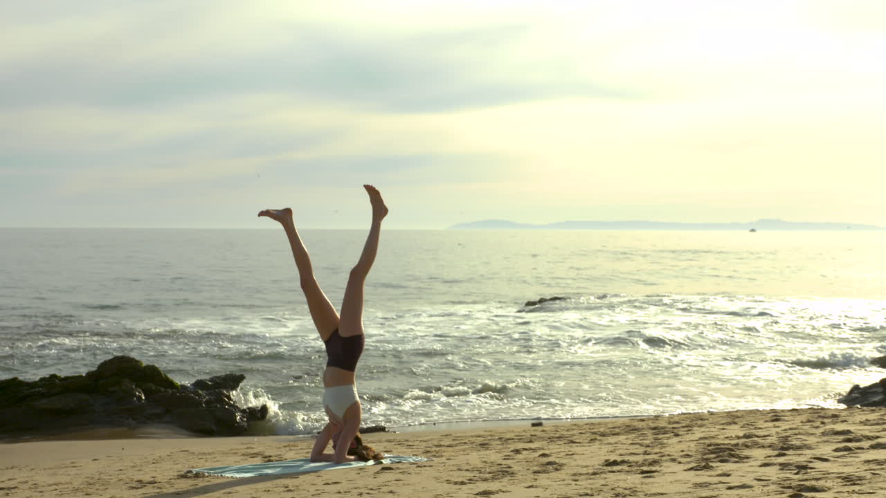 una atractiva joven practicando yoga en una hermosa playa de california