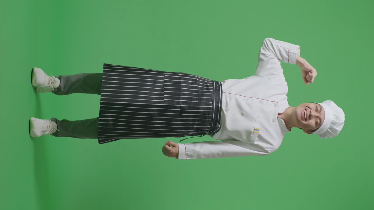 Full Body Of Asian Man Chef Smiling And Flexing His Bicep While Standing In The Green Screen Background Studio