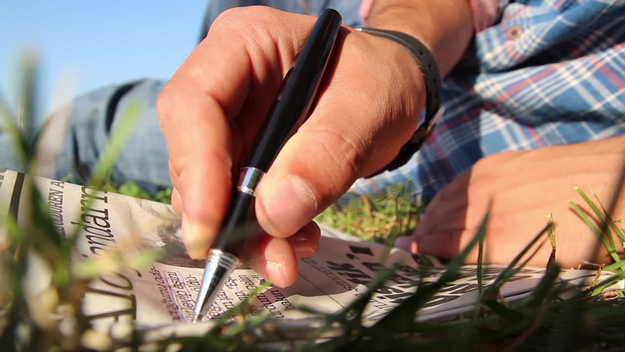 joven leyendo un periódico con un lápiz