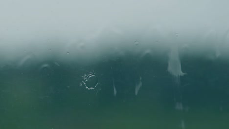 close view drops fall on glass against field silhouette