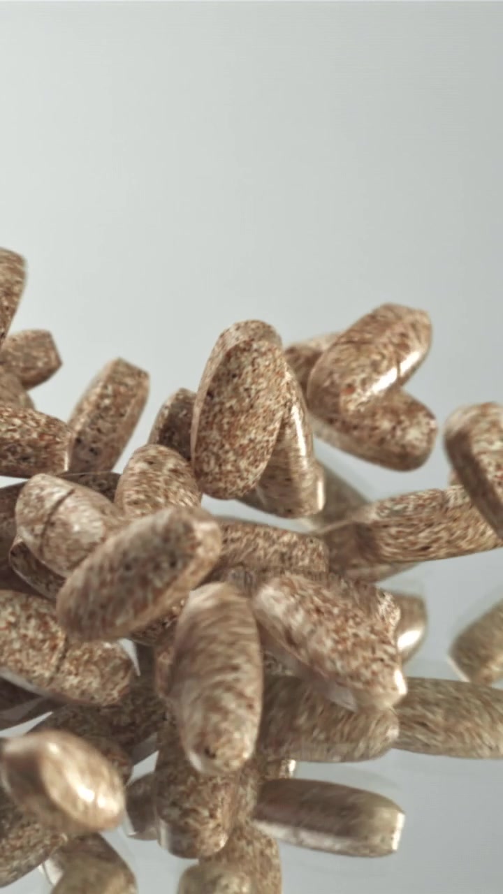 Brown Pills Falling in Slow Motion onto a Reflective Surface