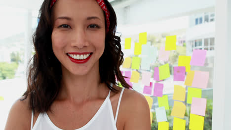 una mujer ejecutiva sonriente de pie con los brazos cruzados en la oficina 4k