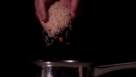 hands dropping rice into cooking pot