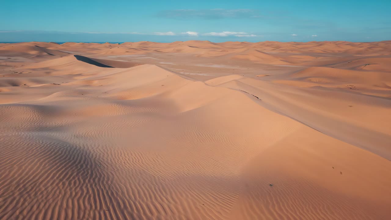 Drone in movimento che rivela una cresta di dune di sabbia centrata nel deserto, mostrando increspature e depressioni in ombra