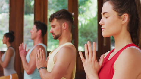 diverse group practicing yoga position with eyes closed during yoga class at studio