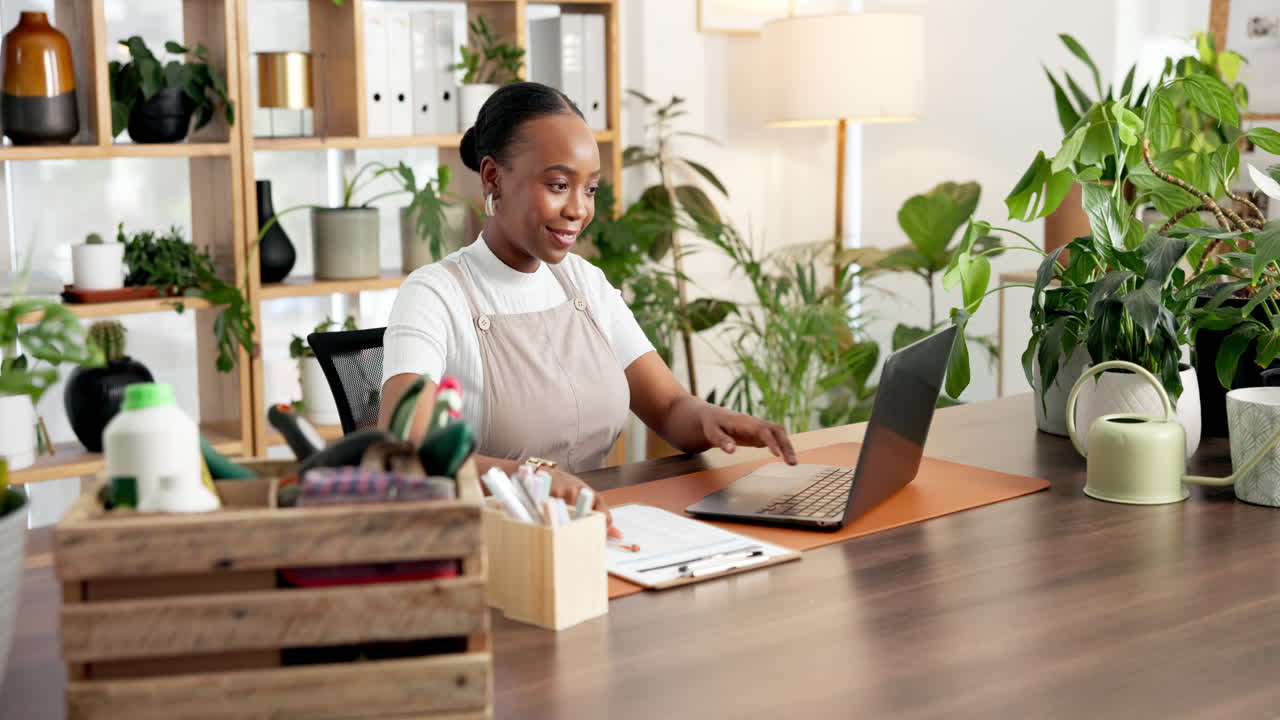 Young Woman Working on Laptop and Writing in a Plant-Filled Home Office