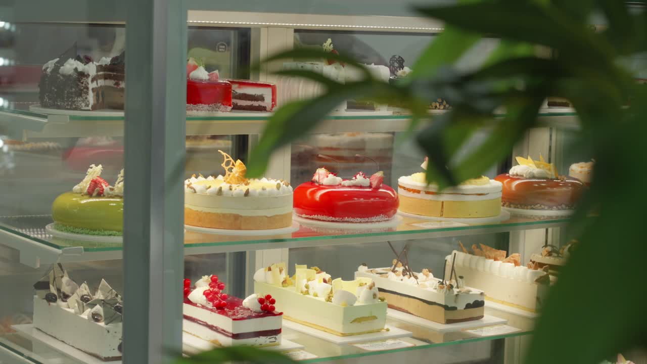 Showcase filled with elegant multi-layered cakes and decorative desserts in a bakery shop.
