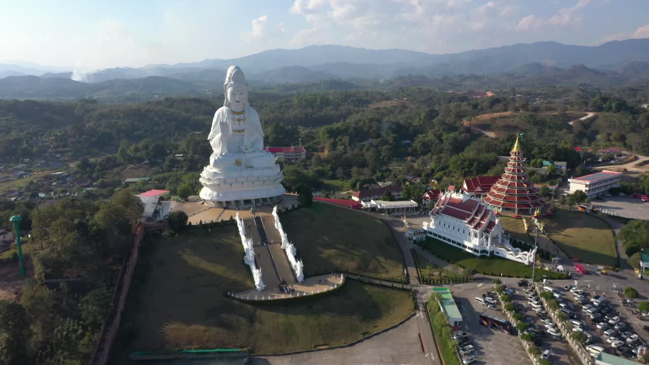 drone aéreo de wat huay pla kang gigante estatua grande blanca y templo de pagoda con montañas en chiang rai, tailandia